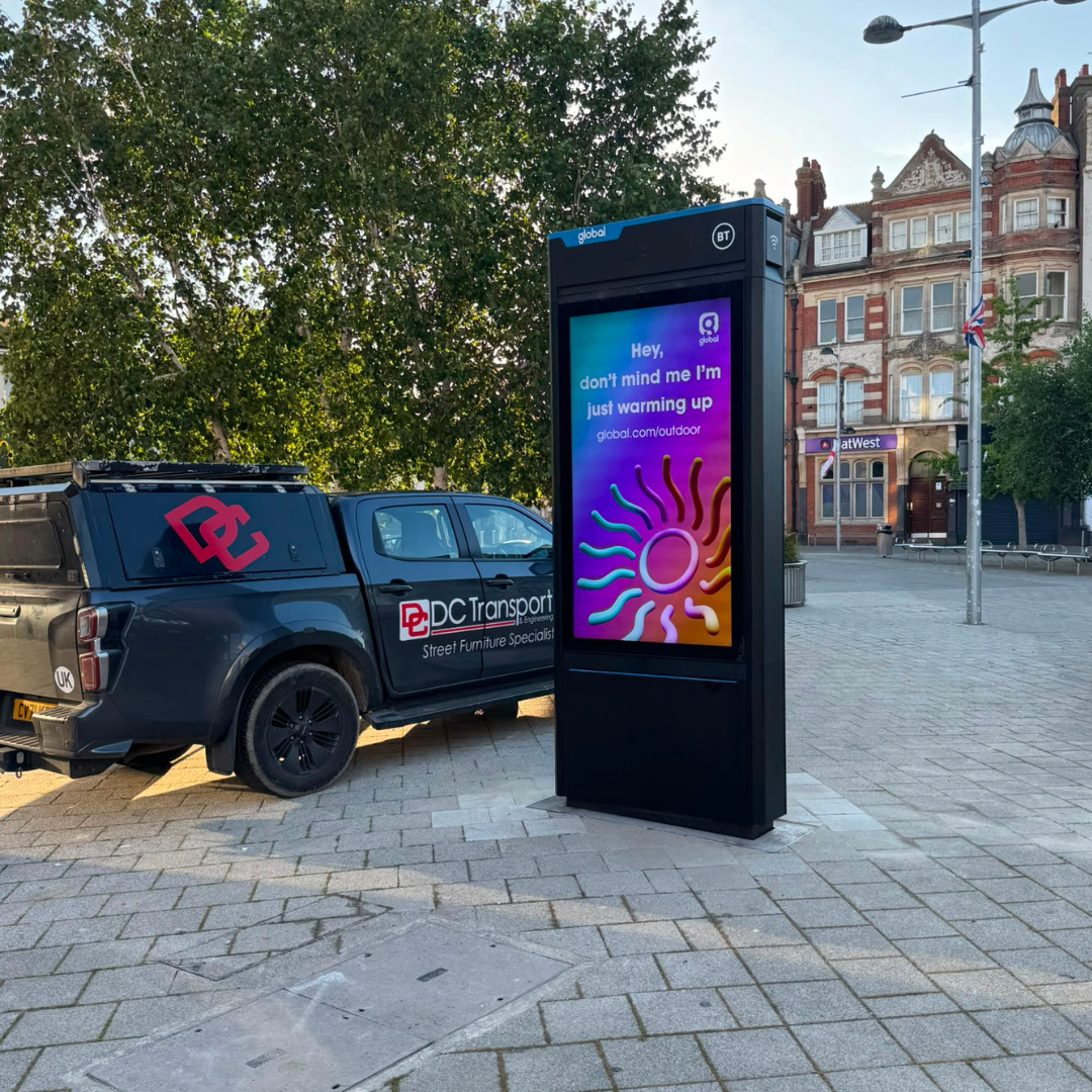 DC Transport and Engineering pickup truck parked next to a newly installed digital street hub advertising panel.
