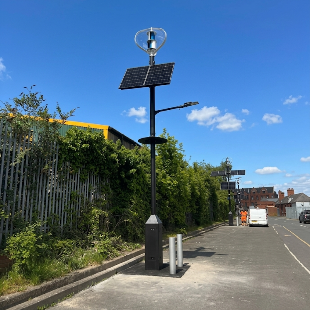 A close up view of a sustainable streetscape column featuring solar panels and a wind turbine assembly.